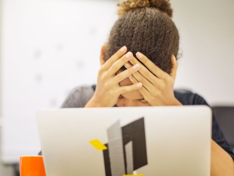 Frau vor dem Laptop legt ihre Kopf in die Hände.