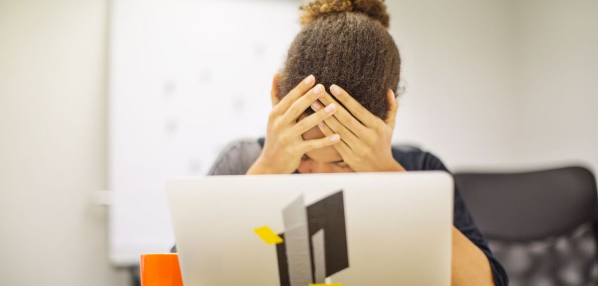 Frau vor dem Laptop legt ihre Kopf in die Hände.