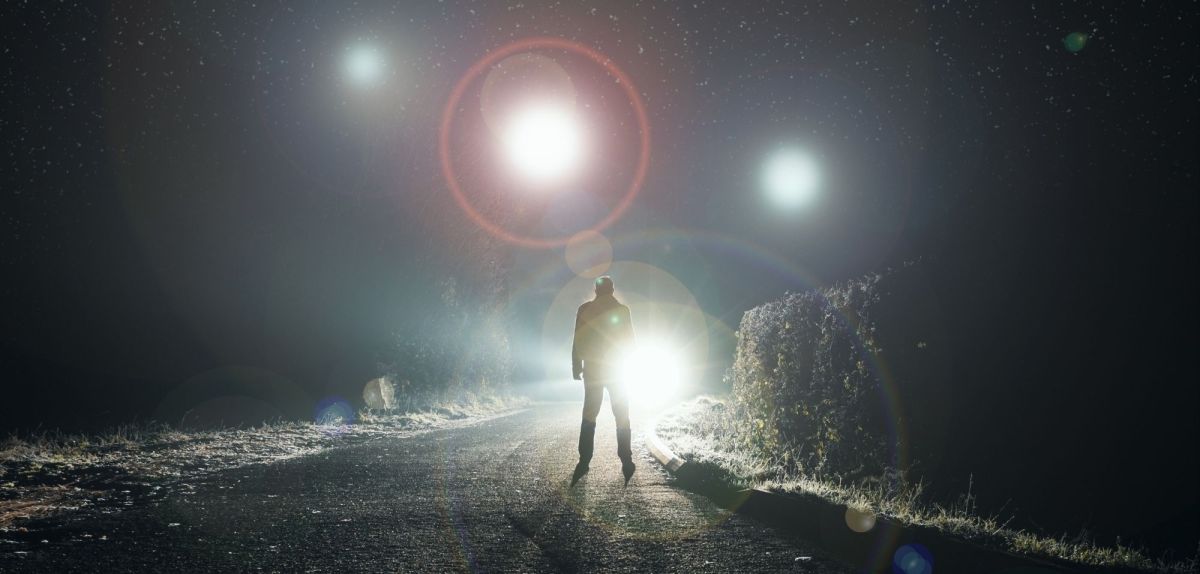 Mensch steht auf einer Straße voller Lichter.