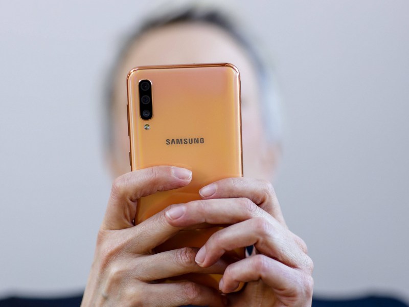 Person hält Smartphone in beiden Händen von sich weg