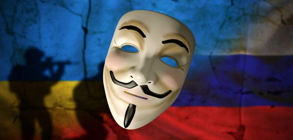 Guy Fawkes-Maske vor einer Russland- und einer Ukraine-Flagge
