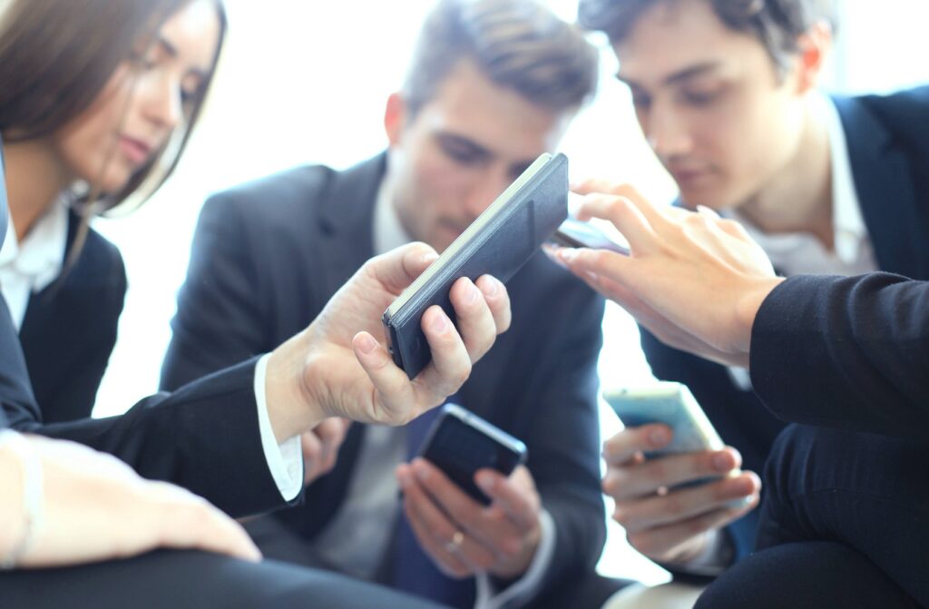 Geschäftspersonen halten Smartphones aneinander 