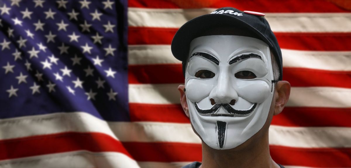 Anonymous-Maske vor einer USA-Flagge.