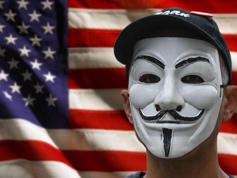 Anonymous-Maske vor einer USA-Flagge.