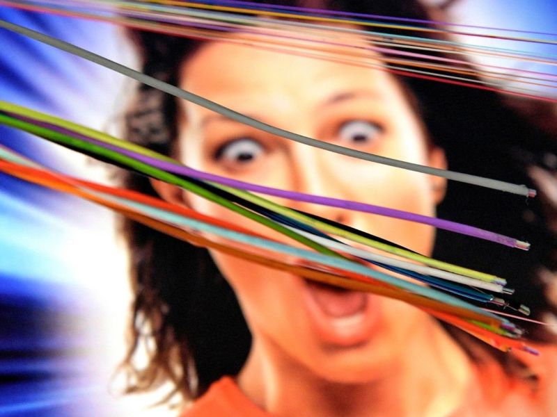 Glasfaserkabel, im Hintergrund eine Anzeige mit einer Frau mit aufgerissenen Augen.