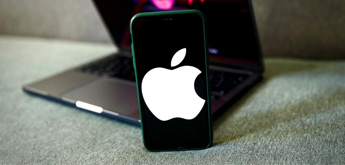 Ein iPhone mit Apple-Logo vor einem Laptop.