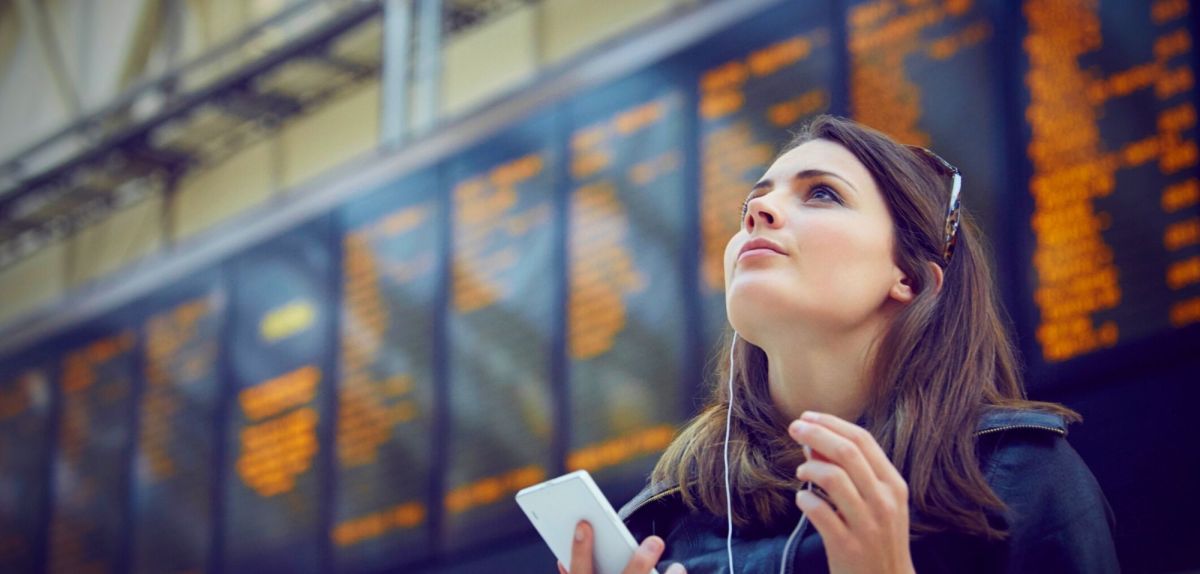 Frau mit Handy am Bahnhof