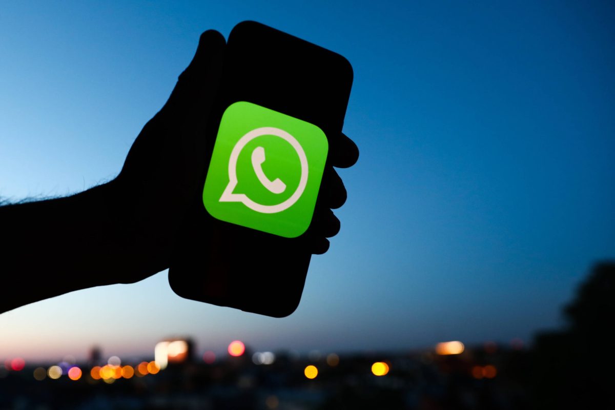 WhatsApp Logo auf Smartphone in Himmel gehalten