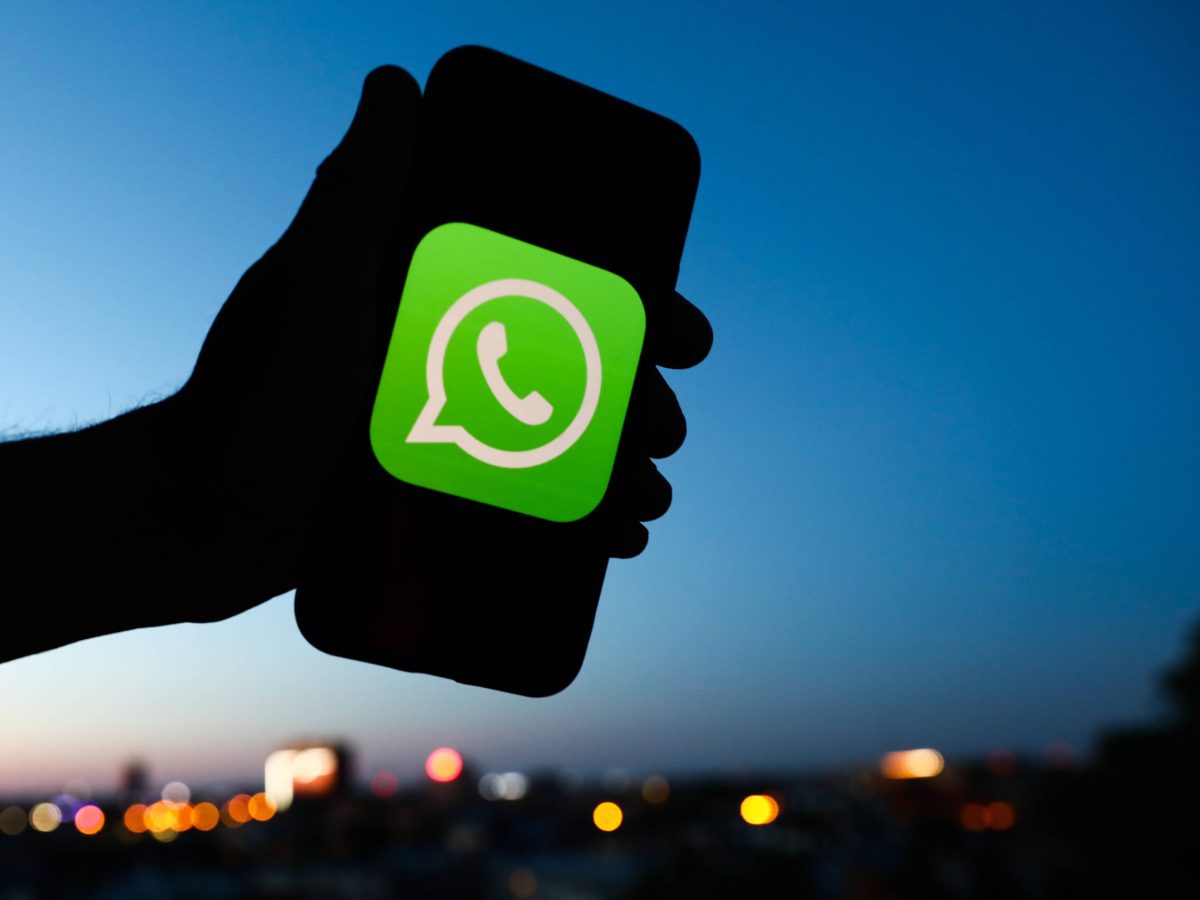 WhatsApp Logo auf Smartphone in Himmel gehalten