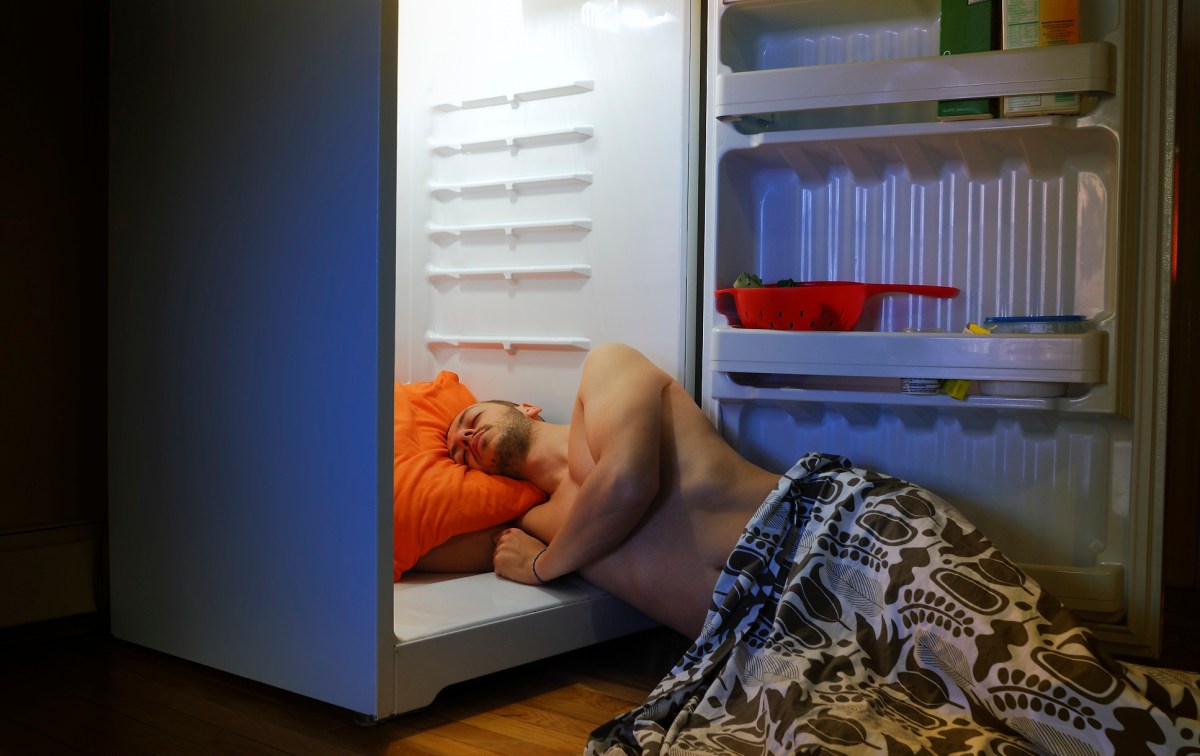 Mann schläft bei Hitze im Kühlschank