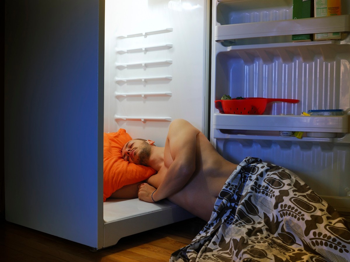 Mann schläft bei Hitze im Kühlschank