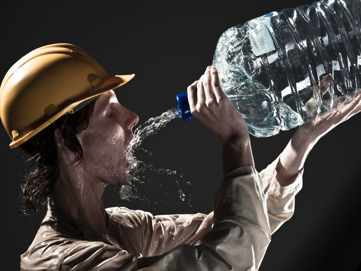 Mann trinkt Wasser aus einer großen Flasche