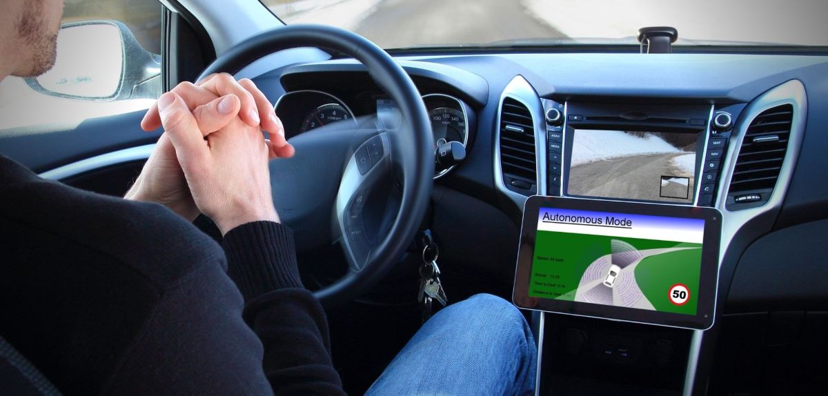 Mann sitzt hinterm Steuer eines Autos ohne Hände am Lenkrad. Selbstfahrendes Auto befindet sich im autonomen Modus.