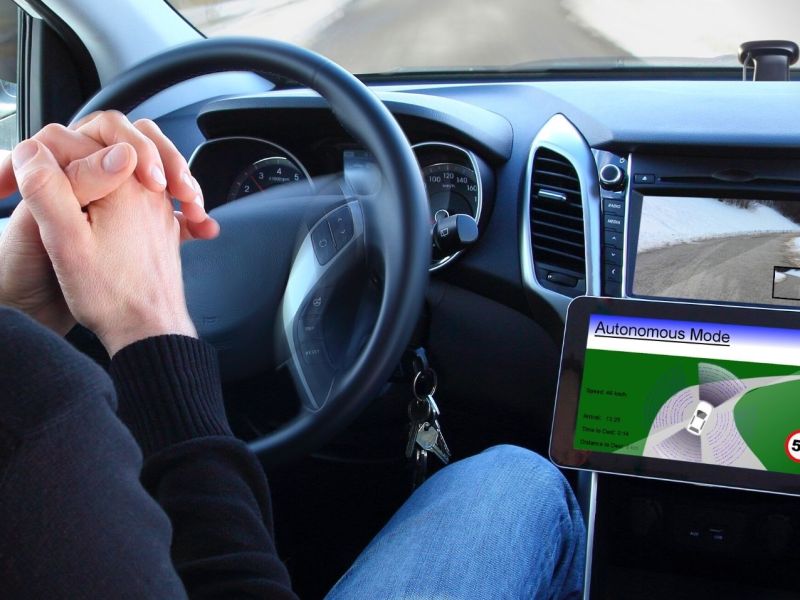 Mann sitzt hinterm Steuer eines Autos ohne Hände am Lenkrad. Selbstfahrendes Auto befindet sich im autonomen Modus.