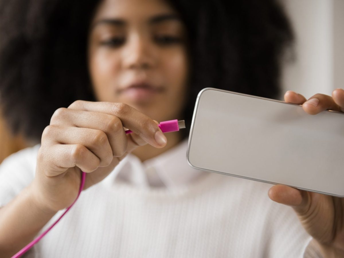 Frau schließt Ladekabel an ein Handy an