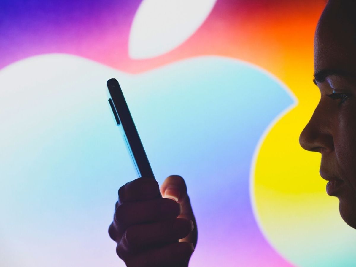 Frau mit iPhone vor einem Apple-Logo