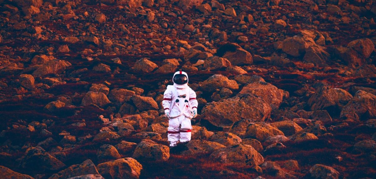 Astronaut vor rotem Geröll