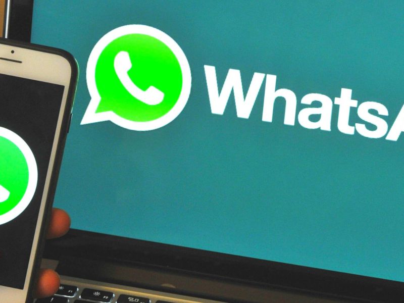 Handy mit WhatsApp-Logo vor Laptop mit demselben Logo.