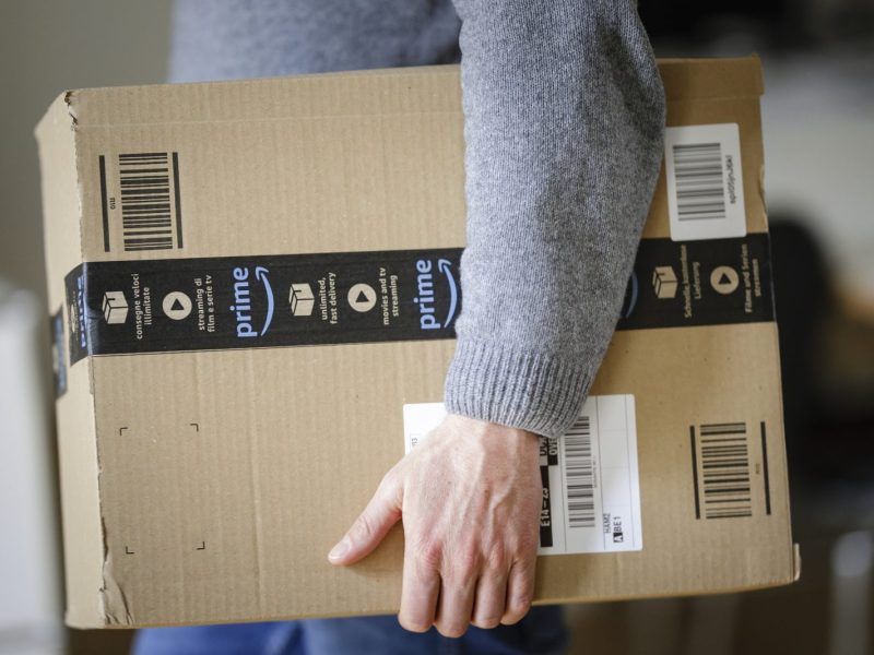 Mann trägt Amazon Prime-Paket unter dem Arm