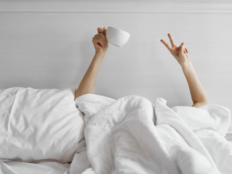 Frau im Bett mit Kaffeetasse