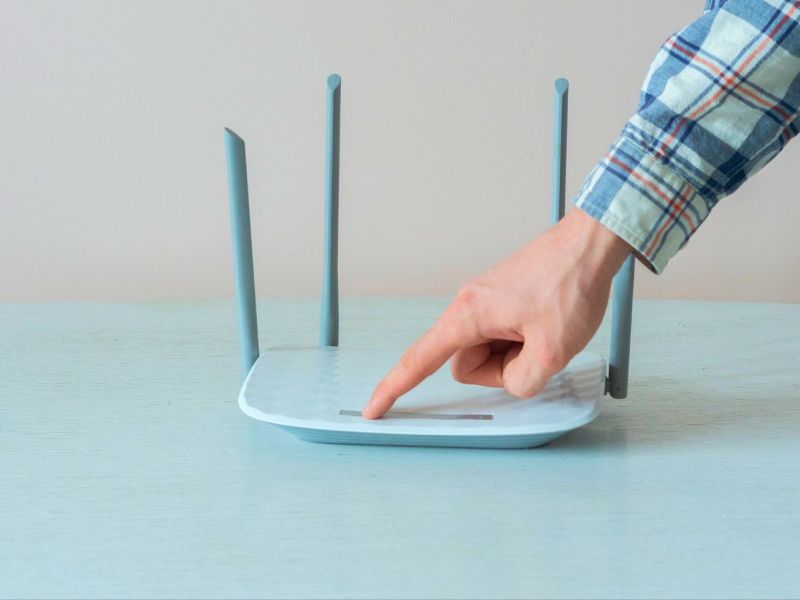 Mann startet den WLAN-Router neu