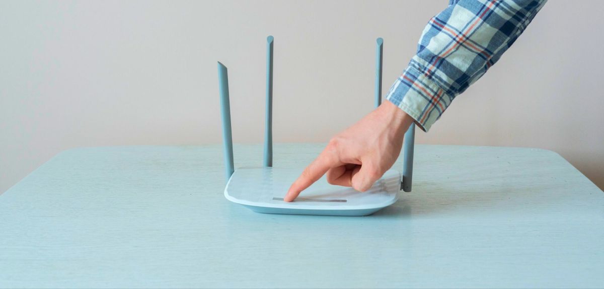 Mann startet den WLAN-Router neu