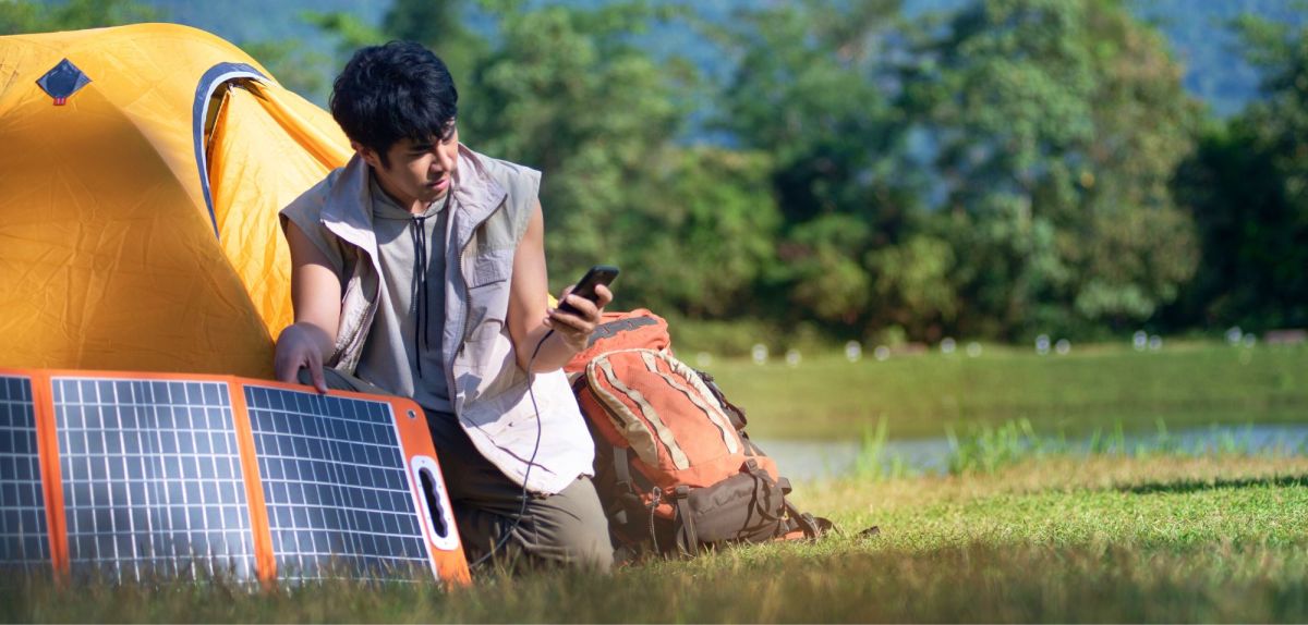 Mann mit Solar-Ladegerät am Handy