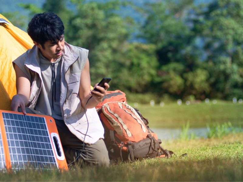 Mann mit Solar-Ladegerät am Handy