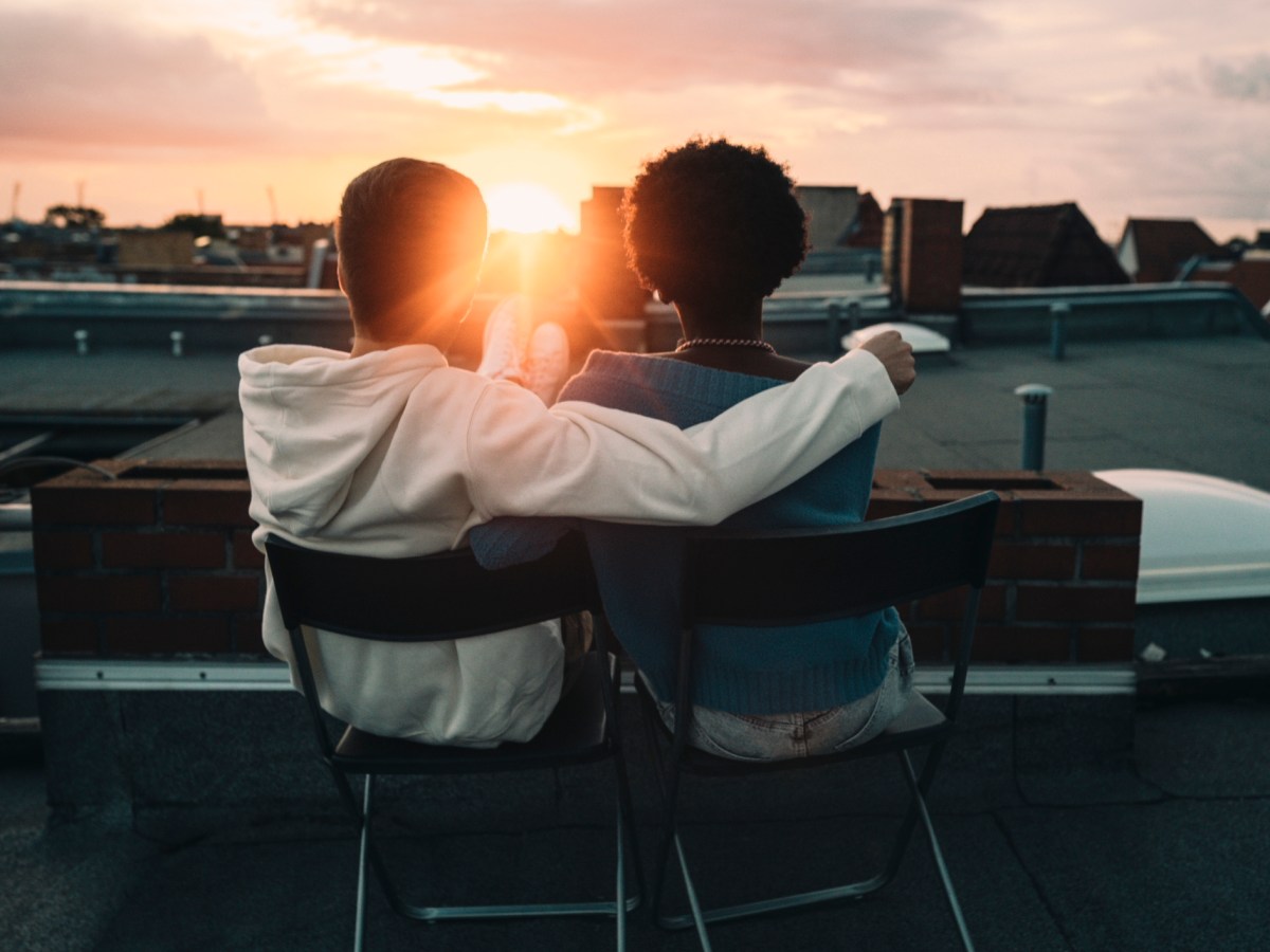 Zwei Personen auf dem Dach beobachten den Sonnenuntergang