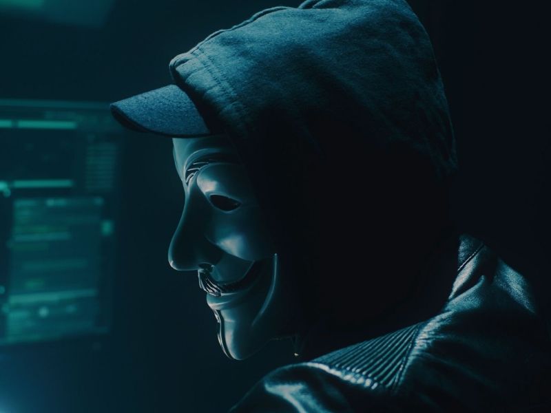 Person mit Guy Fawkes-Maske vor einem Monitor