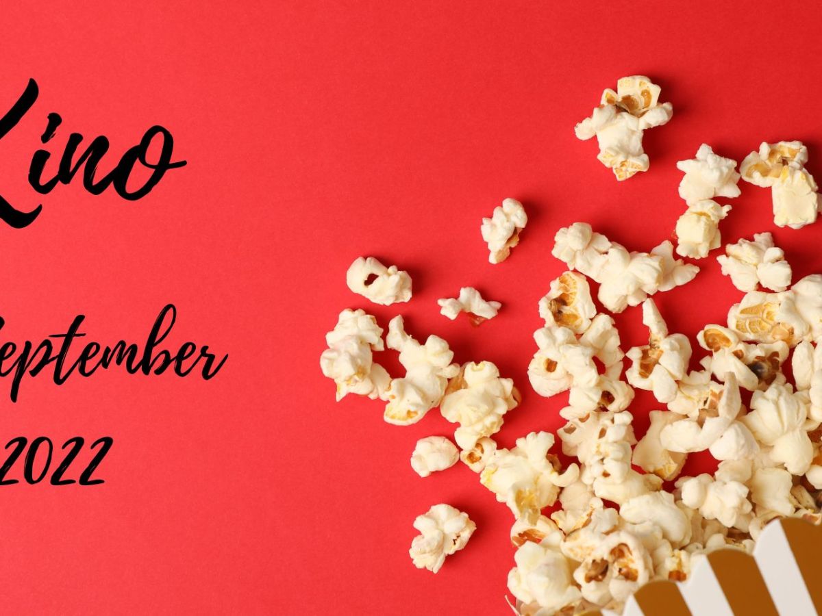 Roter Hintergrund, verschüttetes Popcorn und Schriftzug "Kino im September 2022"