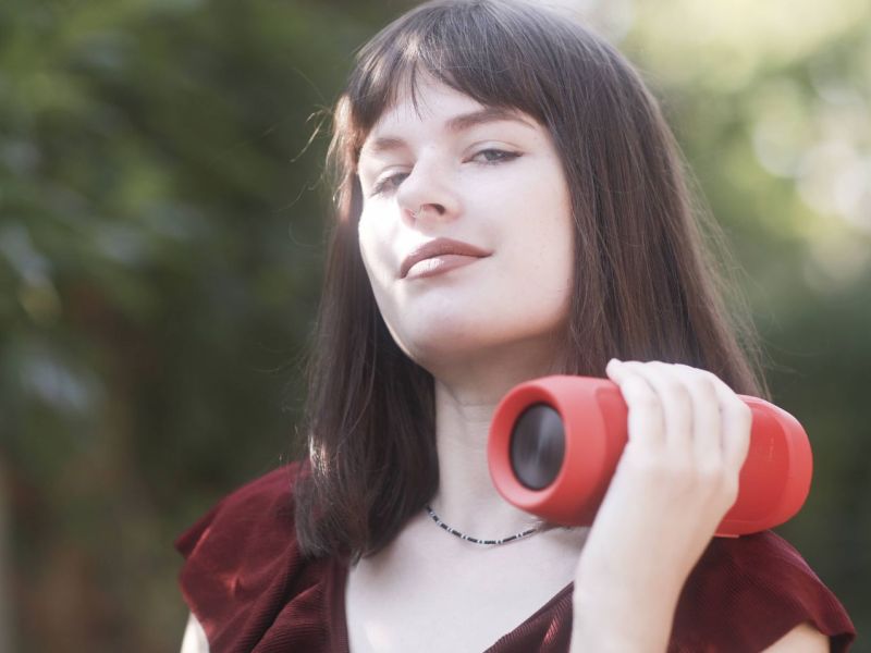 Frau hält Bluetooth-Lautsprecher in der Hand