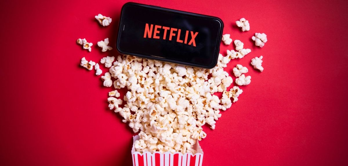 Netflix-Logo auf einem Handy, Tüte Popcorn ausgeschüttet.