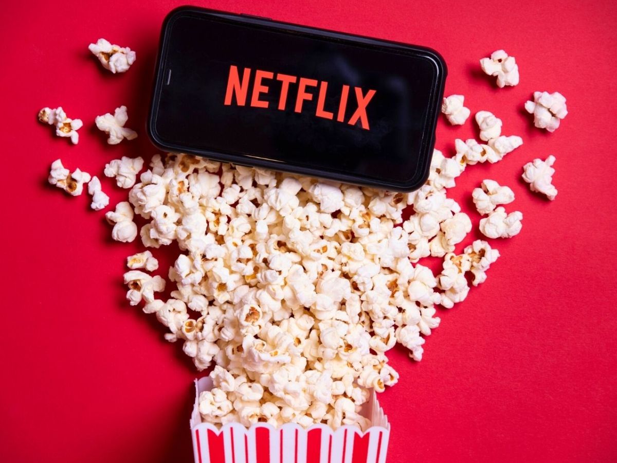 Netflix-Logo auf einem Handy, Tüte Popcorn ausgeschüttet.