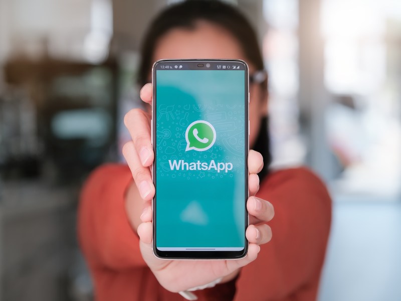 Frau hält Handy mit WhatsApp in die Kamera