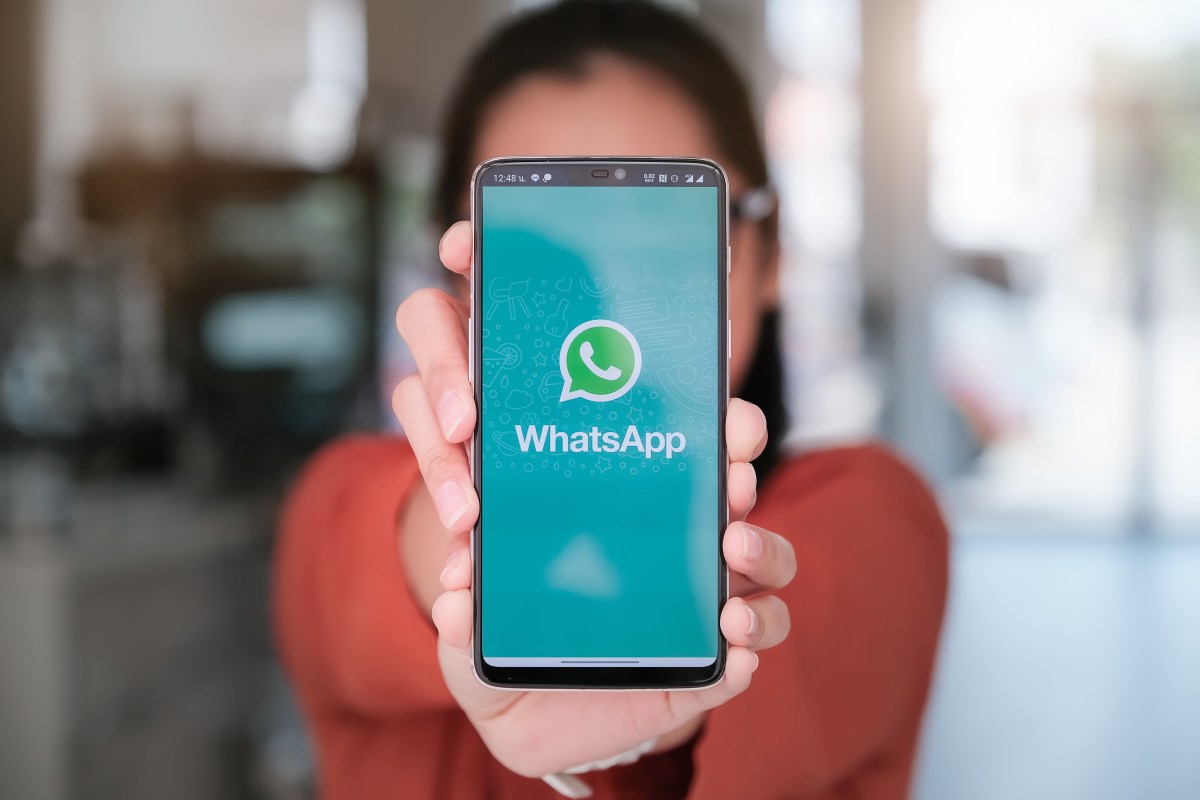 Frau hält Handy mit WhatsApp in die Kamera