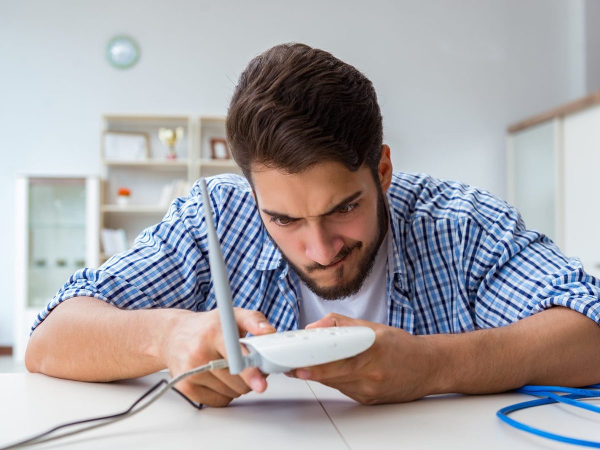 Mann hält WLAN-Router in der Hand