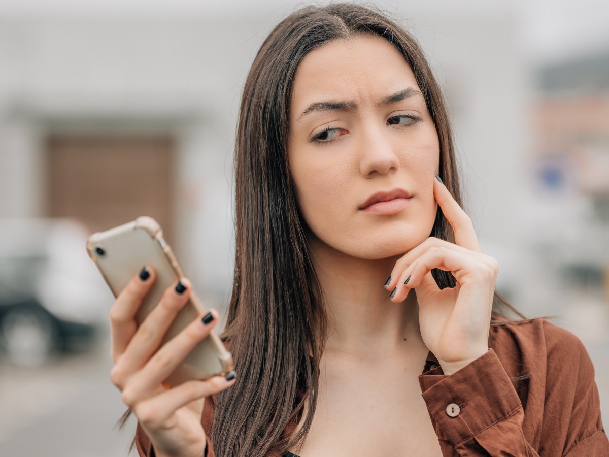 Frau schaut skeptisch auf ihr Smartphone.
