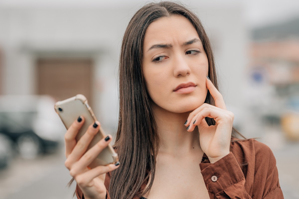 Frau schaut skeptisch auf ihr Smartphone.