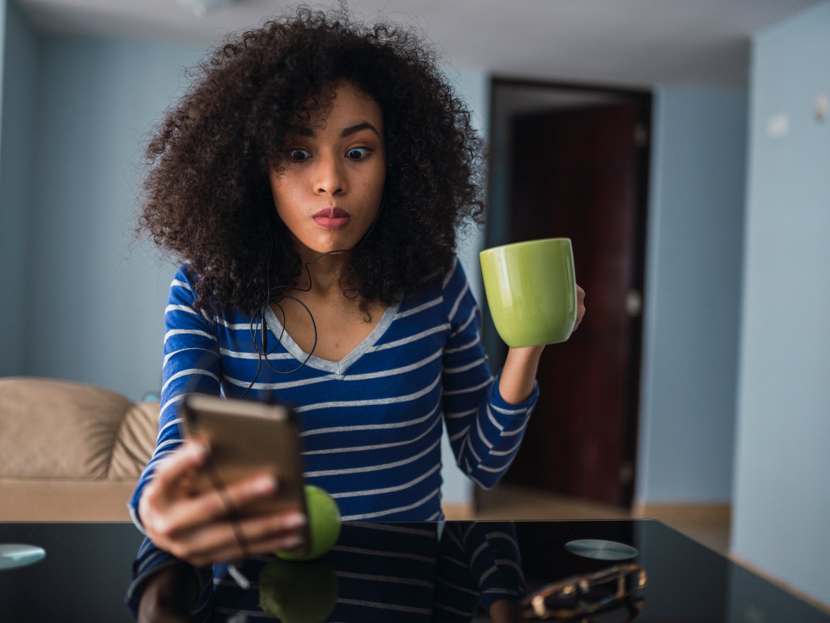 Frau mit Handy und Tasse in der Hand