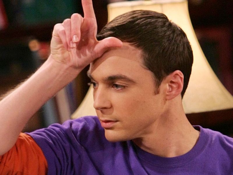 Jim Parsons als Sheldon Cooper zeigt in "The Big Bang Theory" das "Loser"-Handzeichen vor seiner Stirn.