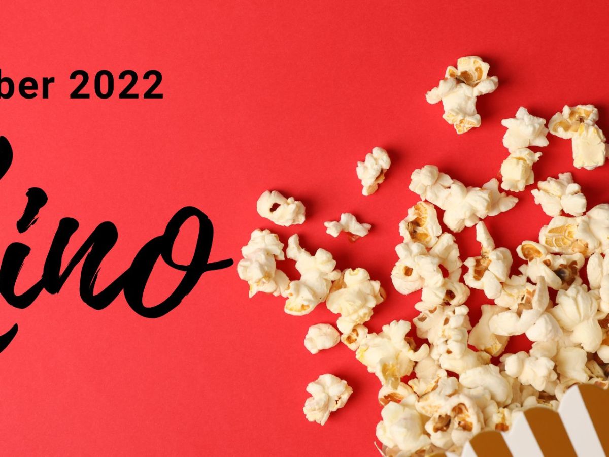 Tüte Popcorn ausgeschüttet über rotem Untergrund.