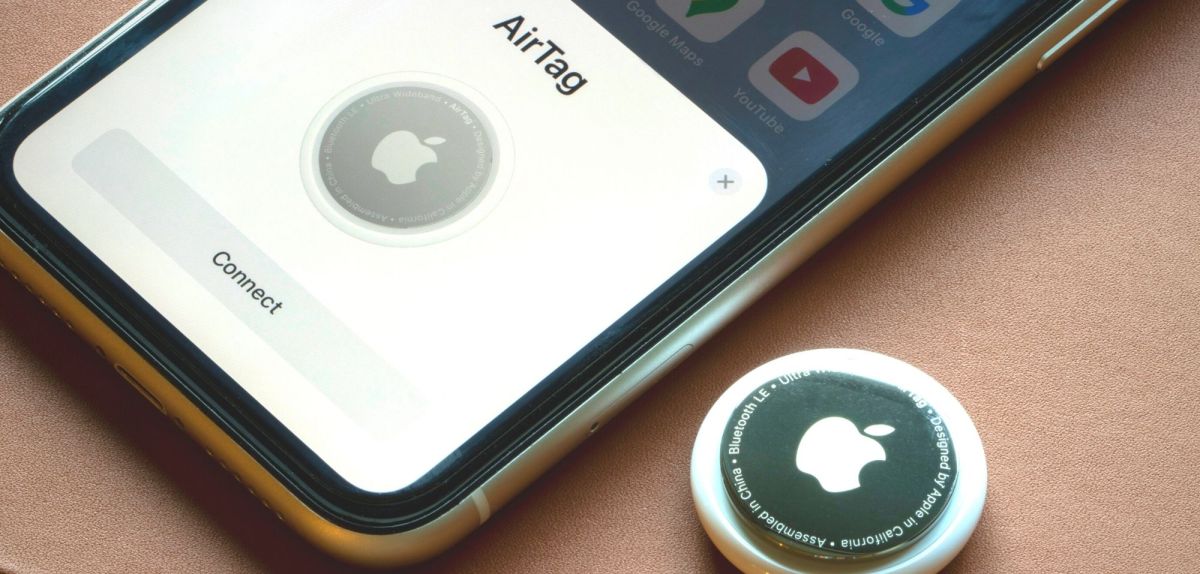 Ein Apple AirTag neben einem iPhone.