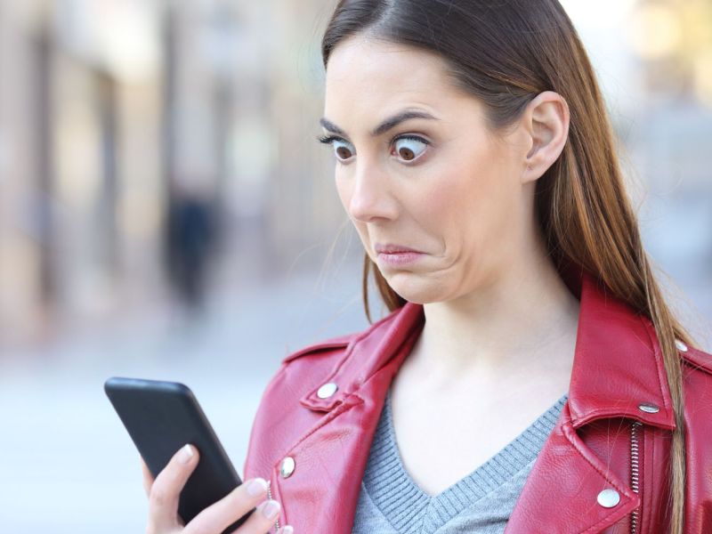 Frau schaut verwirrt auf Smartphone samt vieler Apps