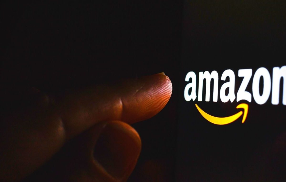 Ein Finger zeigt auf das Amazon-Logo auf einem dunklen Bildschirm.