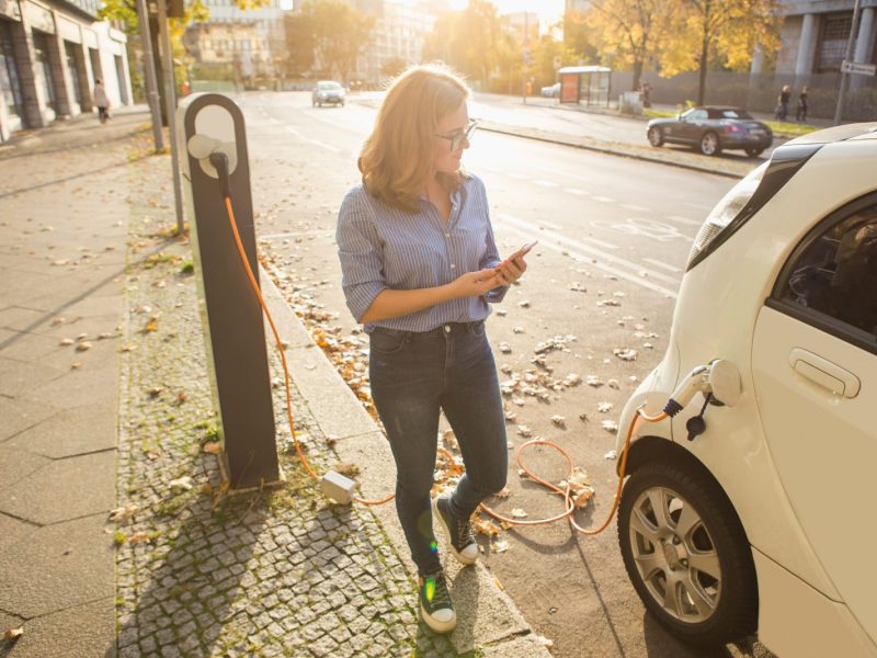 Frau lädt Elektroauto