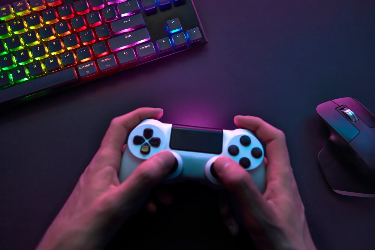 Gaming Controller in Hand vor Maus und Tastatur