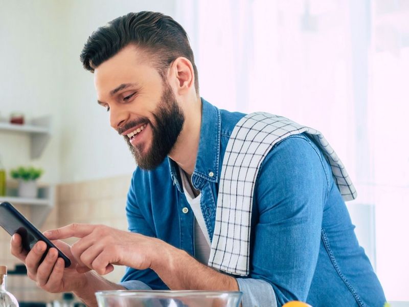 Mann mit Smartphone in der Küche