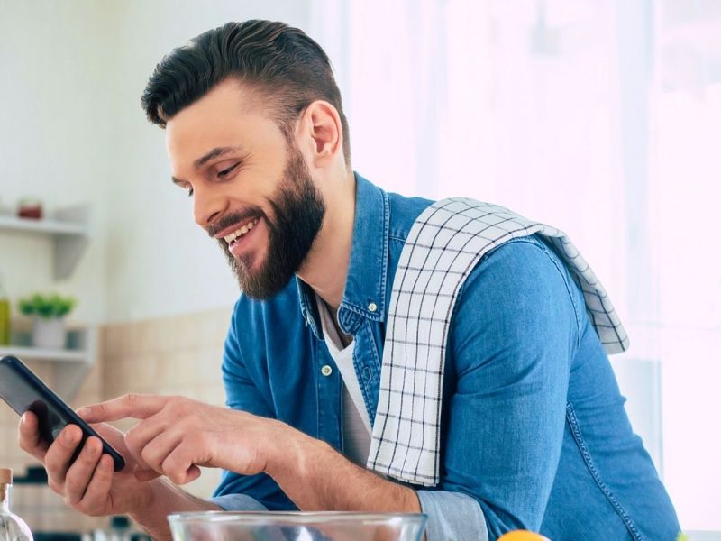 Mann mit Smartphone in der Küche