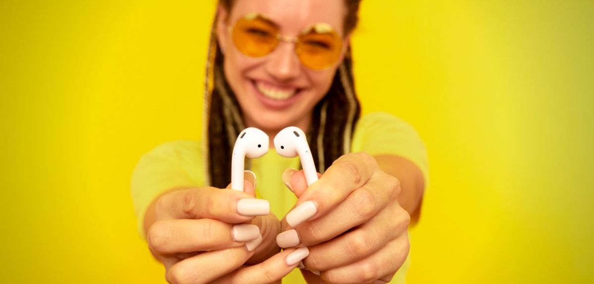 Frau hält AirPods in die Kamera